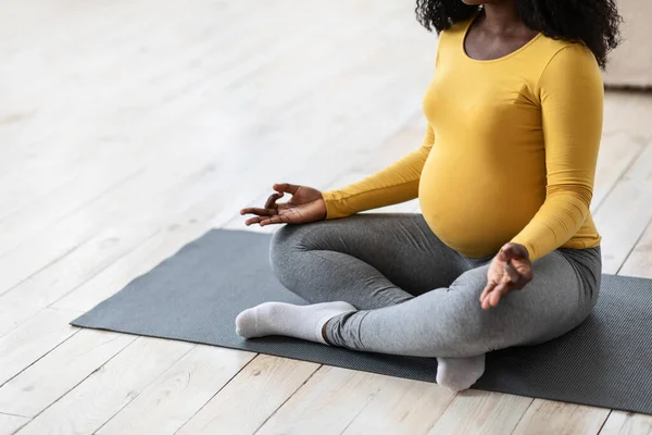 Mujer embarazada irreconocible meditando en casa o en un gimnasio — Foto de Stock
