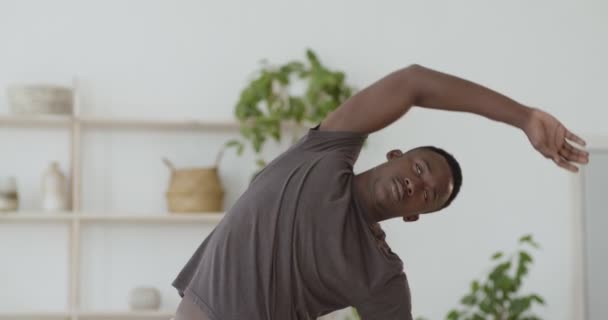 Jovem americano africano treinando em casa, inclinando-se para os lados — Vídeo de Stock