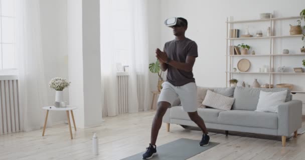 アフリカ系アメリカ人の男でVRヘッドセットは、自宅で前方に運動肺を行う,オンラインビデオチュートリアルを見て — ストック動画