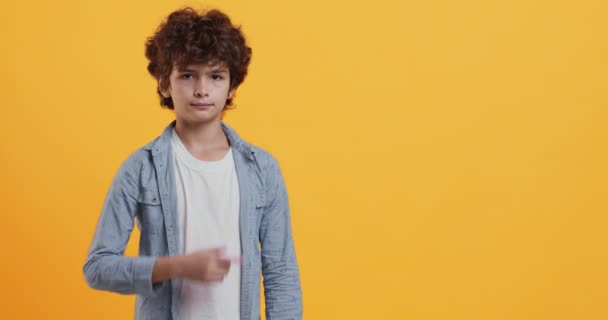 Tolle Werbung. Emotionaler Junge gestikuliert zur Seite und zeigt Kopierraum auf orangefarbenem Hintergrund — Stockvideo