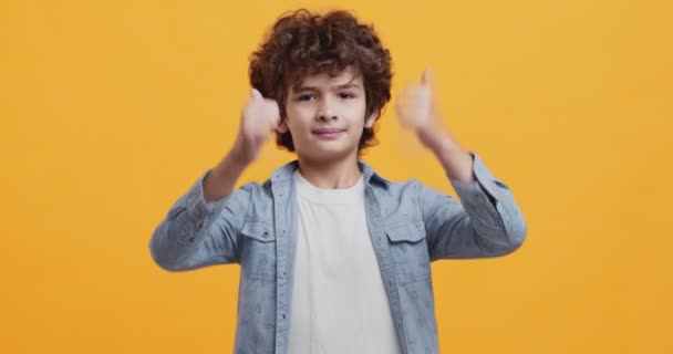 Kinderen vinden het leuk. Vrolijke krullende jongen gebaren duimen omhoog, akkoord, goedkeuring concept — Stockvideo