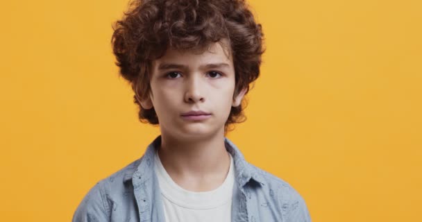 Uroczy chłopiec uśmiechnięty do kamery, portret studyjny na pomarańczowym tle — Wideo stockowe