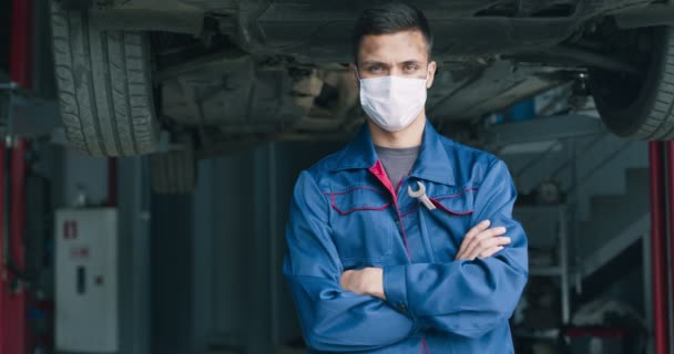 Портрет професійної автомеханіки в захисній медичній масці, позує на станції ремонту автомобілів — стокове відео