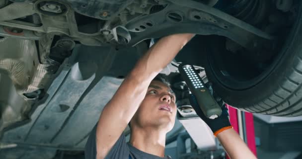 Profesyonel oto tamircisi el feneriyle araba süspansiyon sistemini inceliyor, araç için bakım hizmeti veriyor — Stok video