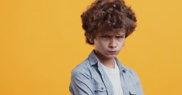 Freche Jungen schmollen Lippen, fühlen sich beleidigt, sich von der Kamera abwenden, orangefarbener Studiohintergrund — Stockvideo