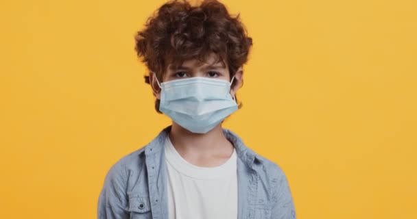 Covid-19 preventive measures. Portrait of little boy wearing protective medical mask and nodding head — Stock Video