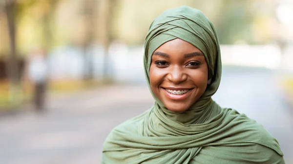 Fekete muszlim nő fogszabályzóval mosolygós kamera pózol szabadban — Stock Fotó