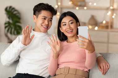 Japon çift evde cep telefonuyla video görüşmesi yapıyor.