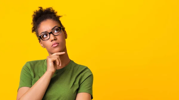 Señora negra en gafas de vista pensando en la pregunta, tocando la barbilla — Foto de Stock