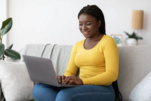 Op afstand werken. Vrolijke zwarte Millennial vrouw met behulp van laptop computer thuis — Stockfoto