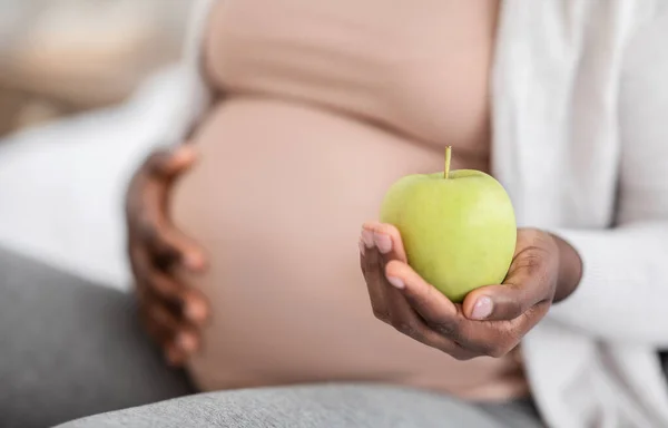 Mulher grávida negra segurando maçã verde orgânica, desfrutando de uma nutrição saudável durante a gravidez — Fotografia de Stock