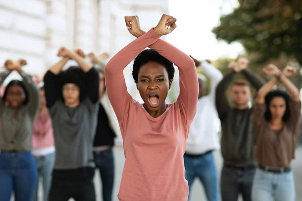 Woman with clenched fists above head protesting with group — Stock Photo, Image