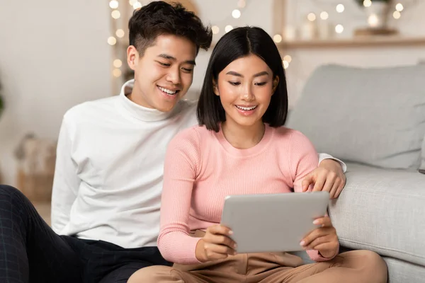 Casal asiático usando tablet computador assistindo filme on-line em casa — Fotografia de Stock