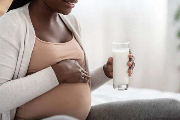 Productos lácteos durante el embarazo. Mujer embarazada negra sosteniendo el vidrio con leche, primer plano — Foto de Stock