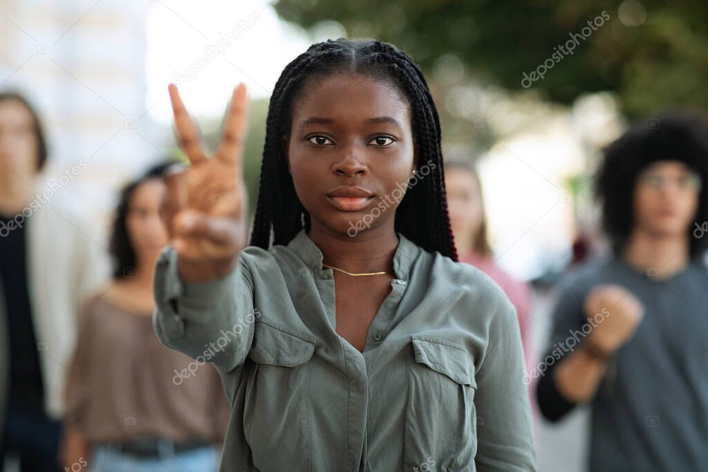 Black woman leading group of international protestors, showing peace gesture