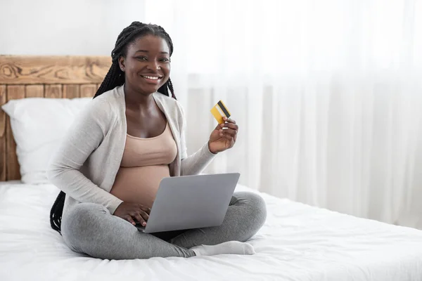 Online winkelen. Gelukkig zwangere vrouw met laptop en creditcard op bed — Stockfoto