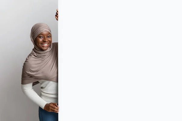 Cheerful black muslim woman in hijab holding big white advertisement board — Stock Photo, Image