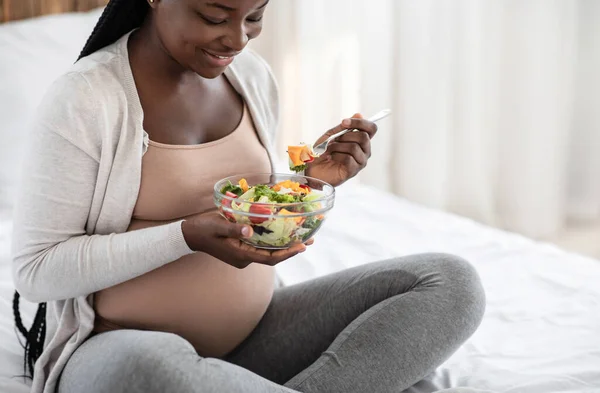 Чорна вагітна жінка тримає чашу зі свіжим салатом, насолоджуючись здоровим харчуванням — стокове фото