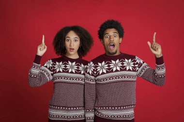 Ağızları açık, parmakları boş, Noel süveteri giymiş Afro-Amerikan erkeği ve bayanı hayrete düşürdü.