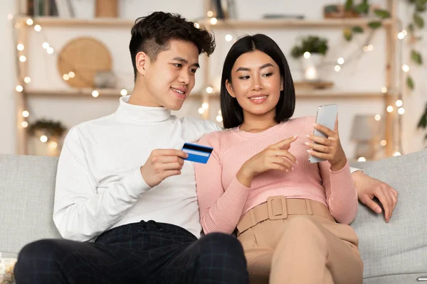 Couple Shopping avec Smartphone et carte de crédit dans le salon — Photo