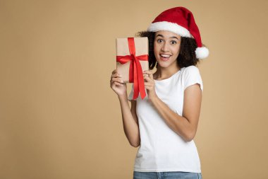 Xmas şapkalı afro-amerikan kadın genç adamın hediyesine şaşırdı ve kameraya ağzı açık baktı.