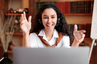 Masada oturan bir kadın, dizüstü bilgisayarında video görüşmesi yapıyor.