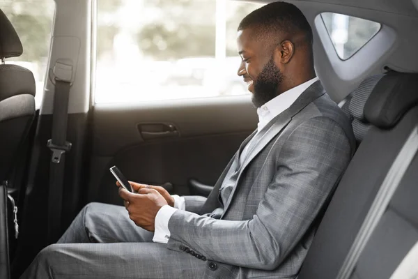 Glücklicher afrikanisch-amerikanischer Geschäftsmann mit Smartphone im Taxi — Stockfoto