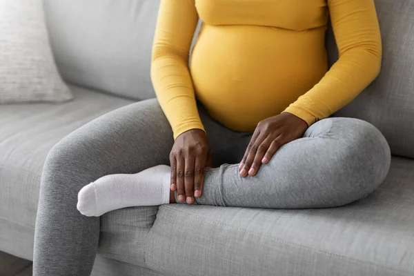 Cortada de mulher grávida negra sentada no sofá em casa — Fotografia de Stock