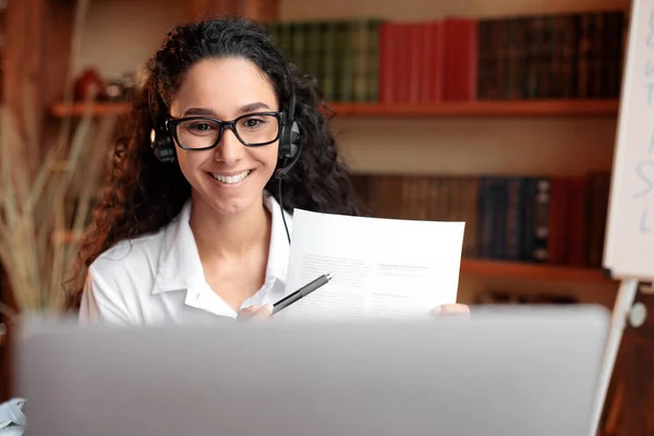 Frau mit Brille sitzt am Schreibtisch und hat Videotelefonie am Laptop — Stockfoto