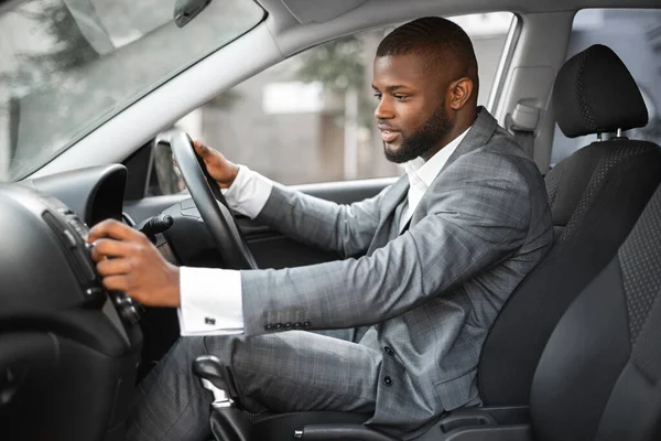Африканський американський бізнесмен, перш ніж переїхати, вмикає музику в машині. — стокове фото