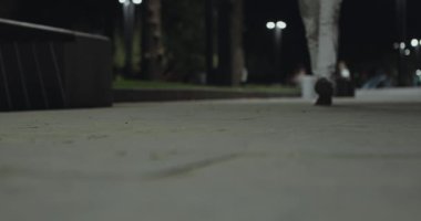 Gece parkında yürürken spor ayakkabılı erkek bacaklarının yakın çekimi.,