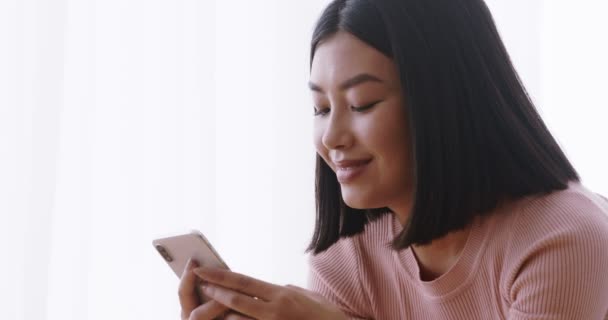 Close up of young asian lady web surfing on cell phone, reading news in social media or watching video content — стоковое видео