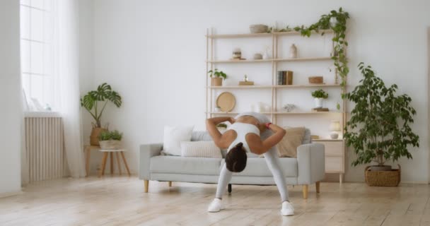 Exercício intensivo em casa. Jovem senhora negra desportiva torcendo seu corpo na sala de estar, câmera lenta — Vídeo de Stock
