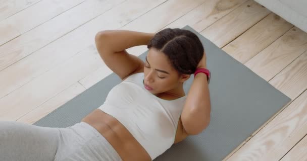 Visão superior na focada senhora afro-americana fazendo exercício crunches, deitado no chão em casa, câmera lenta — Vídeo de Stock