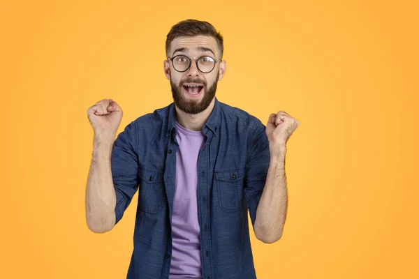 Ganador y concepto de éxito. Muchacho joven excitado haciendo el gesto del SÍ con los puños apretados sobre fondo naranja del estudio —  Fotos de Stock