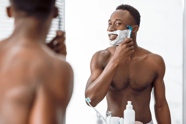 浴室で泡で覆われた顔を剃る恥知らずのアフリカ人男性 — ストック写真