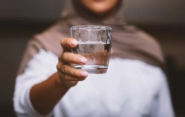 Felismerhetetlen muszlim nő kínál pohár vizet a kamera beltéri — Stock Fotó