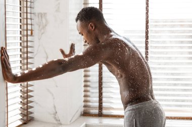 Duşun tadını çıkaran adam banyoda buharlı suyun altında dinleniyor.