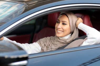 Neşeli Müslüman kadın yeni arabasını kullanıyor.