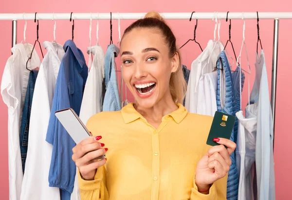 Mujer feliz sosteniendo el teléfono celular y la tarjeta de crédito —  Fotos de Stock