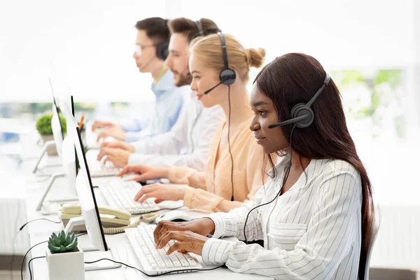Operadores de call center focados com fones de ouvido trabalhando com computadores no escritório de espaço aberto, espaço em branco — Fotografia de Stock