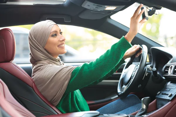 Gelukkig moslim dame rijden alleen verstellen achteruitkijkspiegel — Stockfoto