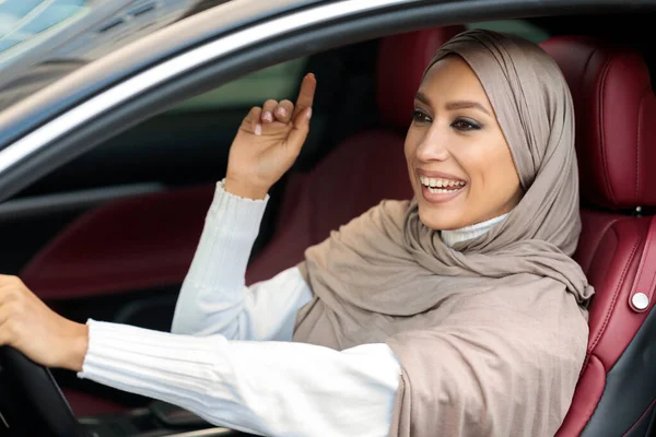 Vrolijke moslim vrouw rijden auto, luisteren naar muziek — Stockfoto