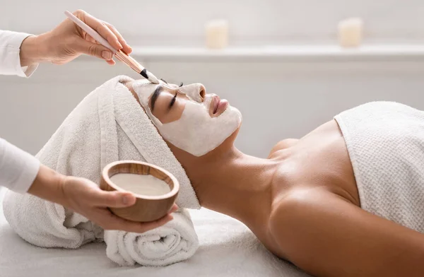 Ansiktsbehandling. Beautist tillämpa lera ansiktsmask till asiatisk kvinna på spa — Stockfoto