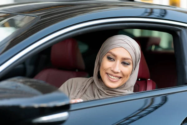 Glimlachende moslim vrouw test rijden auto in stedelijke stad — Stockfoto