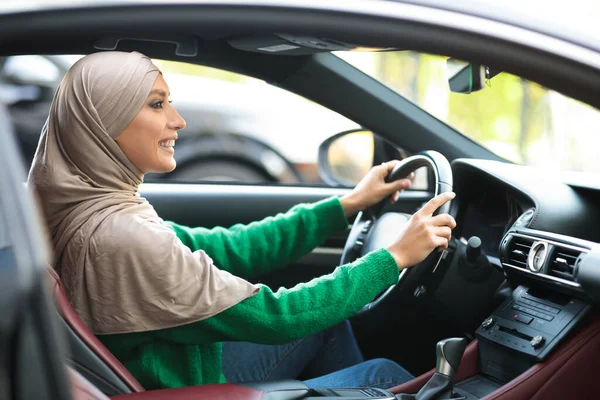 Glimlachende moslim vrouw test rijden nieuwe auto in stedelijke stad — Stockfoto