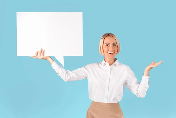 Empresaria positiva sosteniendo la burbuja del discurso sobre fondo azul del estudio, espacio para el diseño, panorama — Foto de Stock