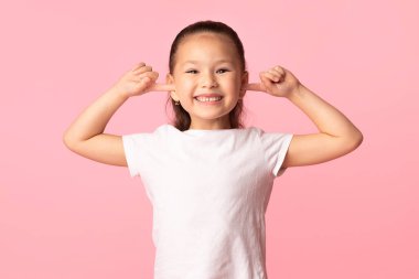 Asyalı çocuk parmaklarını kulaklarına sokup yüzünü buruşturuyor.