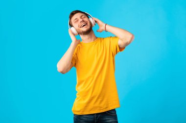 Gülümseyen adam kulaklıklarla ve dansla müzikten hoşlanıyor.