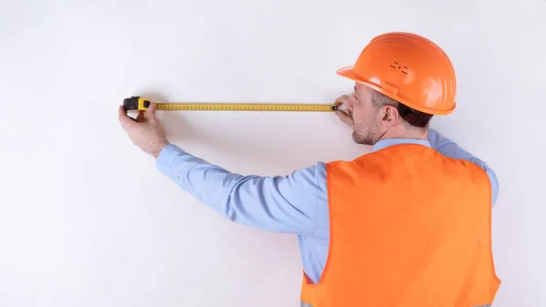 Builder Measuring Wall with Tape-Measure Standing back to Camera, Studio — Φωτογραφία Αρχείου